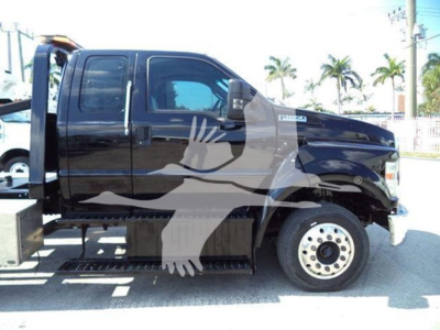 Ford F-650 rollback truck side view showing cab, wheel, and side step with black paint; no legible brand text visible on body from this angle.