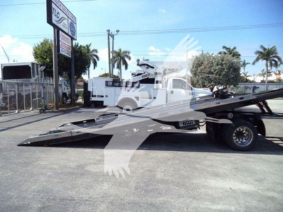 Flatbed rollback tow truck on lot with front view showing Ford F650 with extended wheelbase and hydraulic bed.