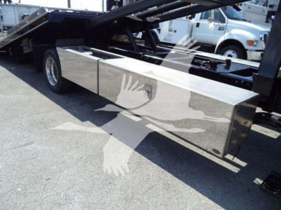 Side view of a rollback tow truck with a polished metal storage box and hydraulic system visible; no readable text on components.