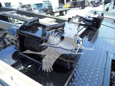 Truck bed winch reel and hydraulic hook system on a Diamond plate surface, with coiled steel cable and winch motor visible.