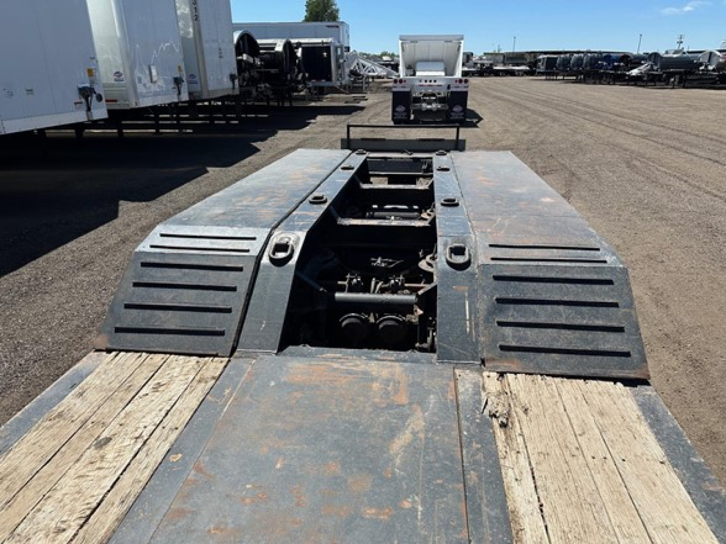Trail King 50 Ton lowboy trailer deck with pony motor access, metal ramps and open engine compartment showing mechanical components.