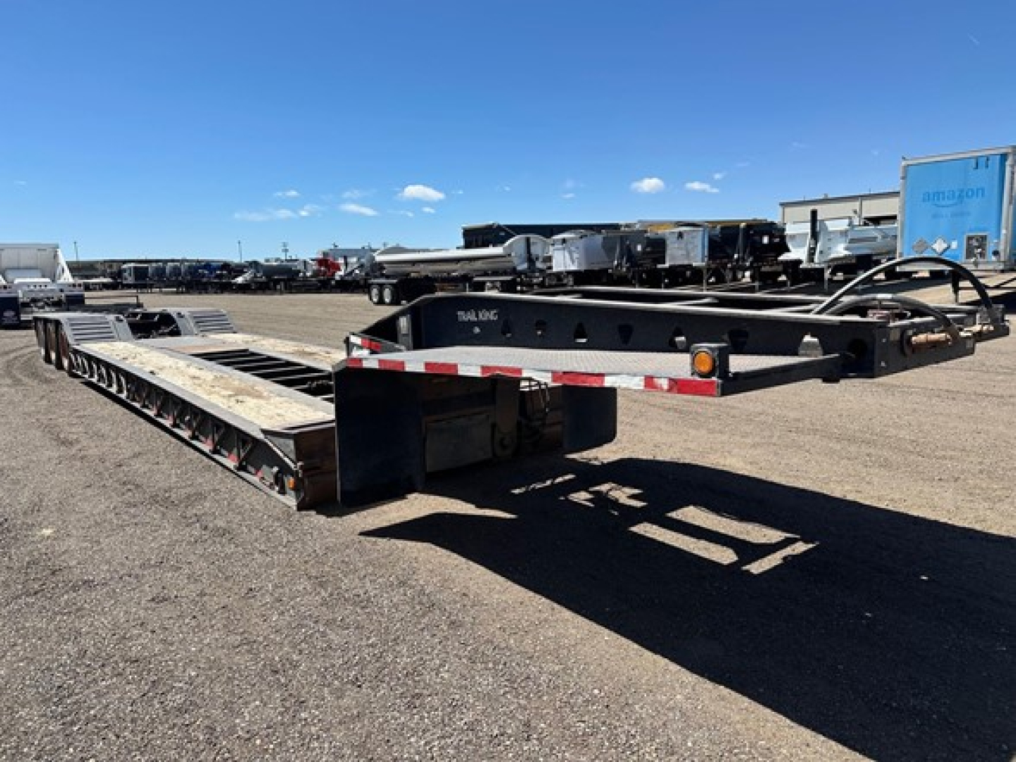 Trail King 50 ton lowboy trailer in a yard, visible ponies and long flatbed section with red/white reflective tape.