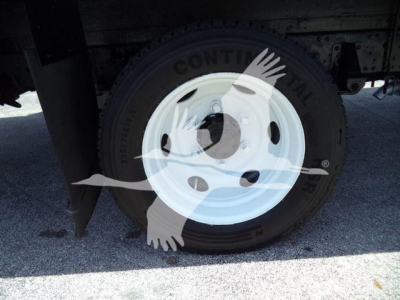 Truck wheel well with a white steel rim and tire, undercarriage visible.
