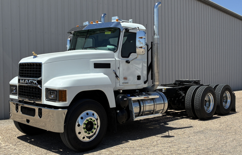 Mack Pi64T conventional daycab truck in white showing front grille and side exhaust stacks.