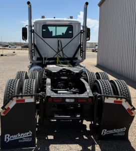 Rear view of a 2027 Mack PI64T conventional daycab truck showing dual rear axles, fifth wheel, and mudflaps with Bruckners Truck & Equipment logos.