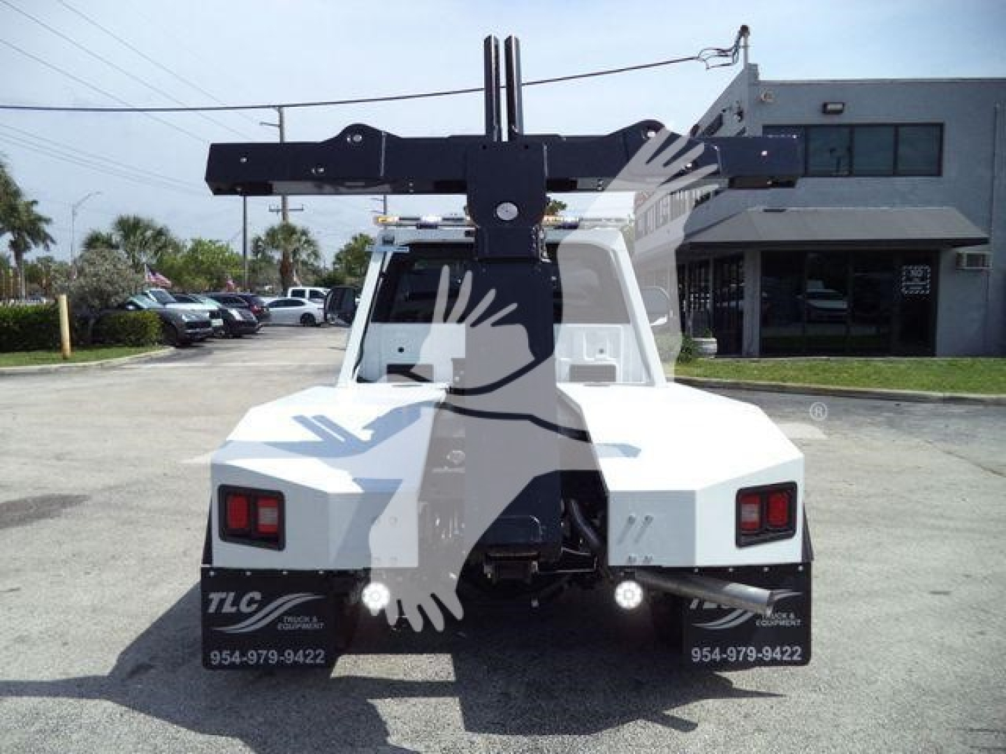 Rear view of a white Ford F-450 utility truck with a large black winch crane arm mounted behind cab, rectangular taillights, and TLC branding on mud flaps; stock number J40065FM visible.