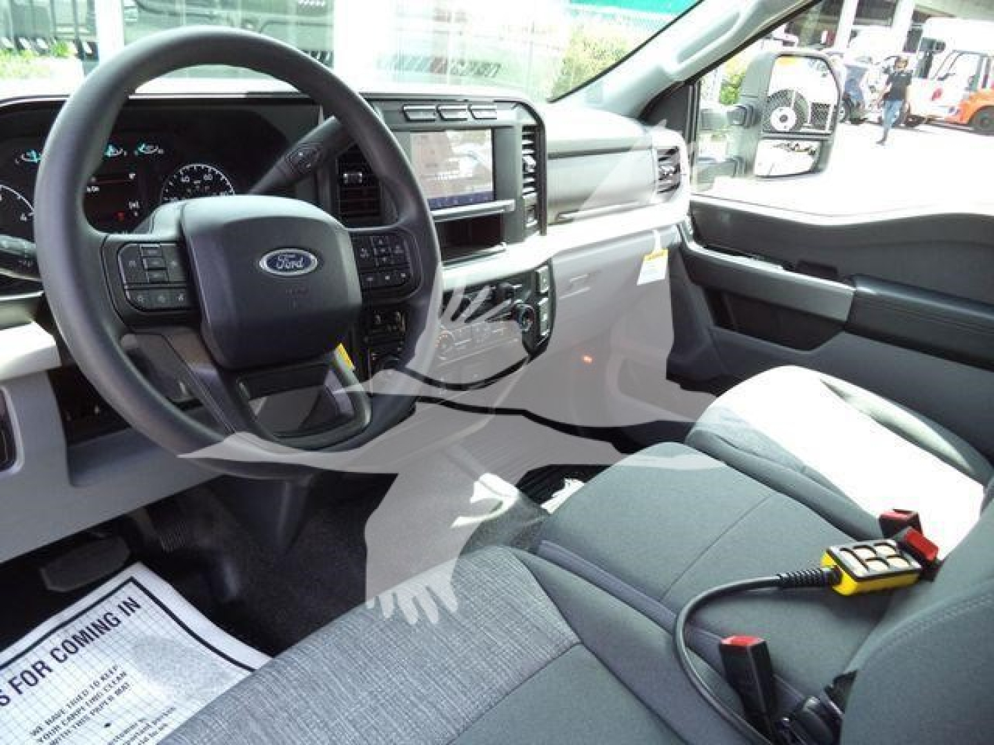 Ford F-450 interior view showing steering wheel, dashboard, and large touchscreen infotainment display with center console; front seats and dashboard details visible.