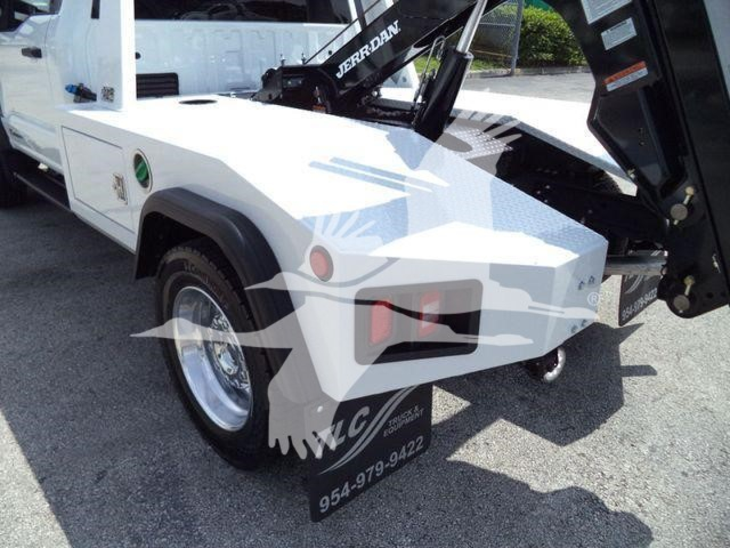 Ford F-450 truck bed with winch equipment mounted, white exterior, close view of rear wheel and towing hitch.