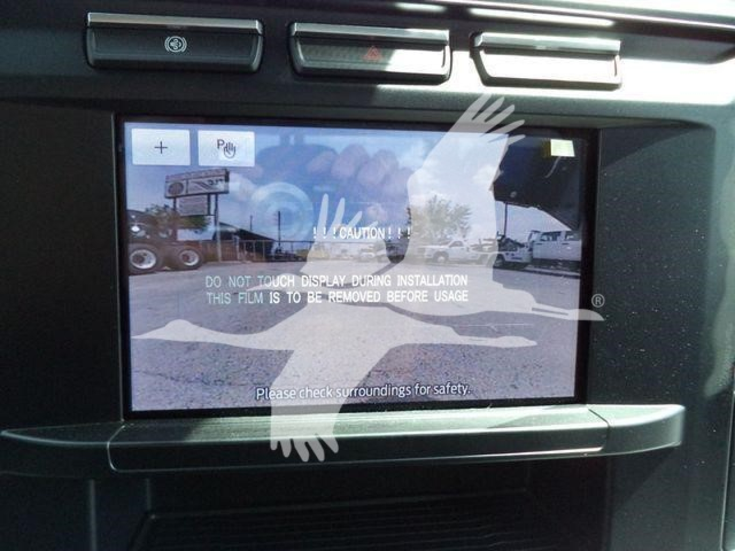 Ford F-450 winch truck interior display showing a rearview monitor with a warning: DO NOT TOUCH DISPLAY DURING INSTALLATION THIS FILM IS TO BE REMOVED BEFORE USAGE. PLEASE CHECK SURROUNDINGS FOR SAFETY.