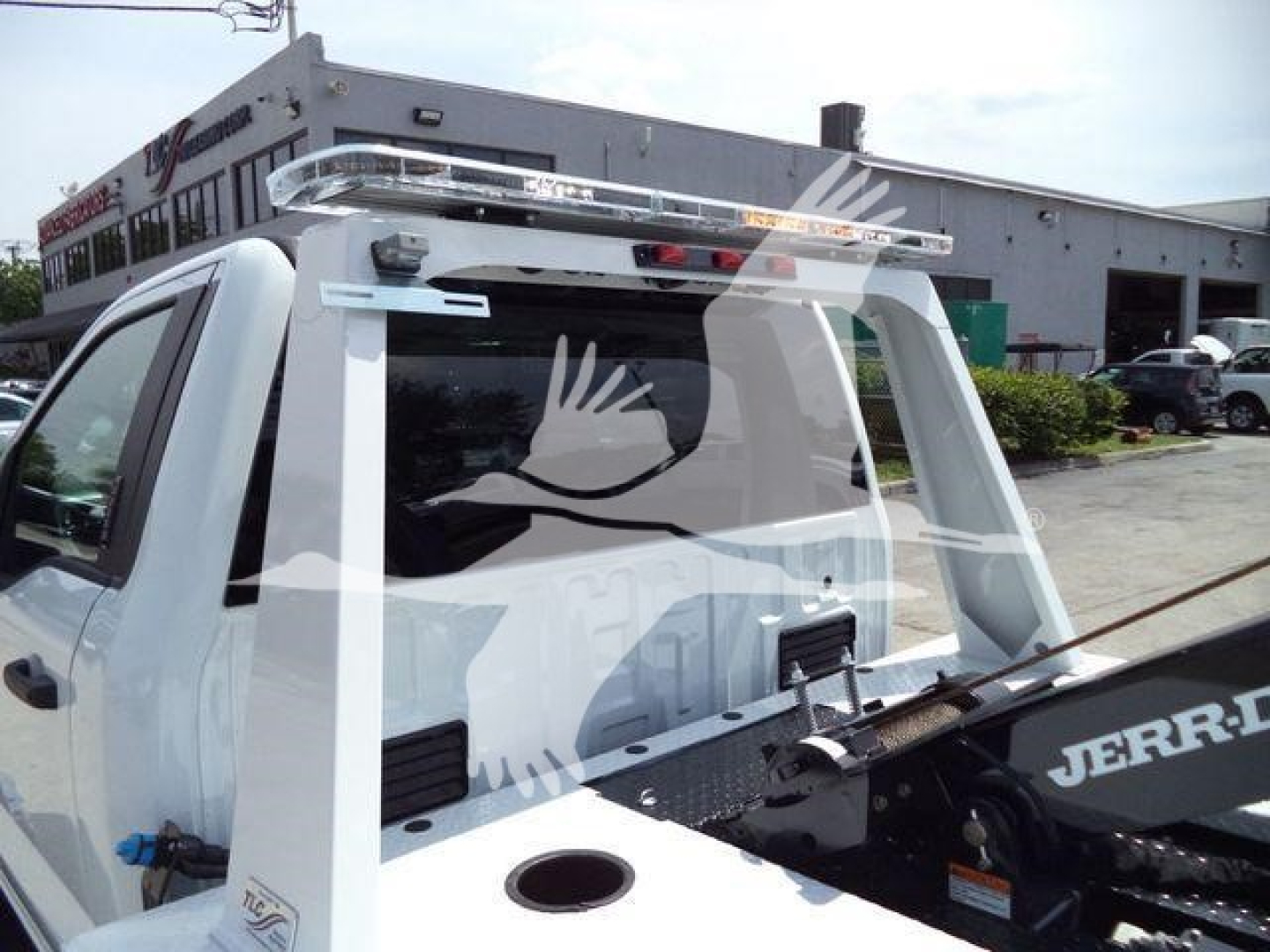 Truck rear view with a winch attachment and light bar mounted on top, white cab, Jerr-Dan winch arm visible.