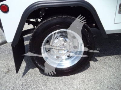 Ford F-450 wheel and wheel well showing a polished alloy rim and tire in a white utility truck body