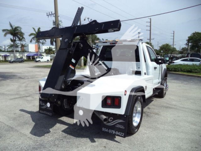 Ford F-450 tow truck with mounted hydraulic winch system at rear, white cab and chassis, black boom arm, tires and wheels, service decals, and rear cargo area visible.