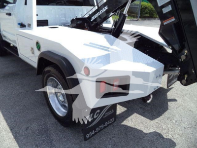 Ford F-450 truck bed with winch equipment mounted, white exterior, close view of rear wheel and towing hitch.