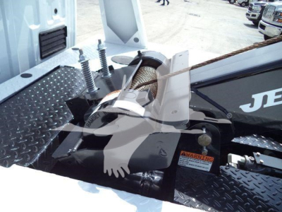 Winch-equipped Ford F-450 truck bed showing hawse fairlead and spool with warning label