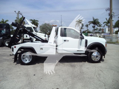 Ford F-450 tow truck/chassis with integrated winch system and white cab, side view showing flatbed with wheel, winch mechanism, and hydraulic arms.