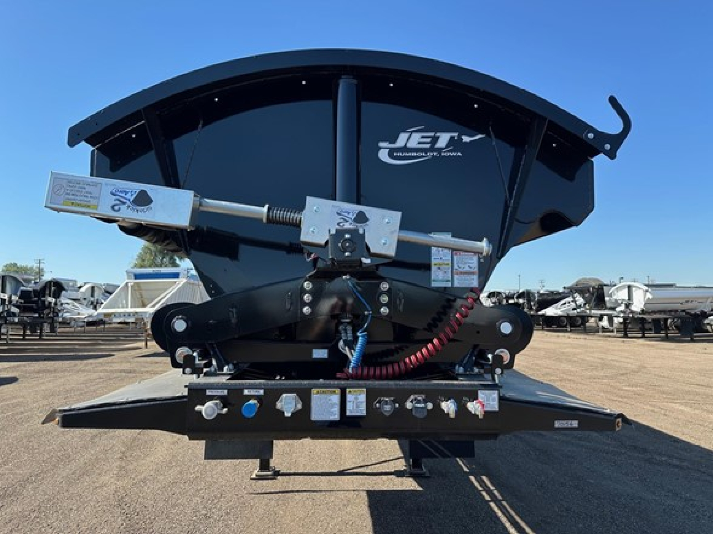 Dump trailer with Jet pivot points per side and tub flex corners showing rear view, with control levers, hoses, and labels on the hitch area.