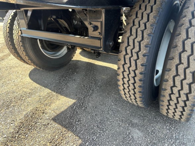Truck trailer undercarriage with dual rear axles and tires, metal frame, suspension components visible.