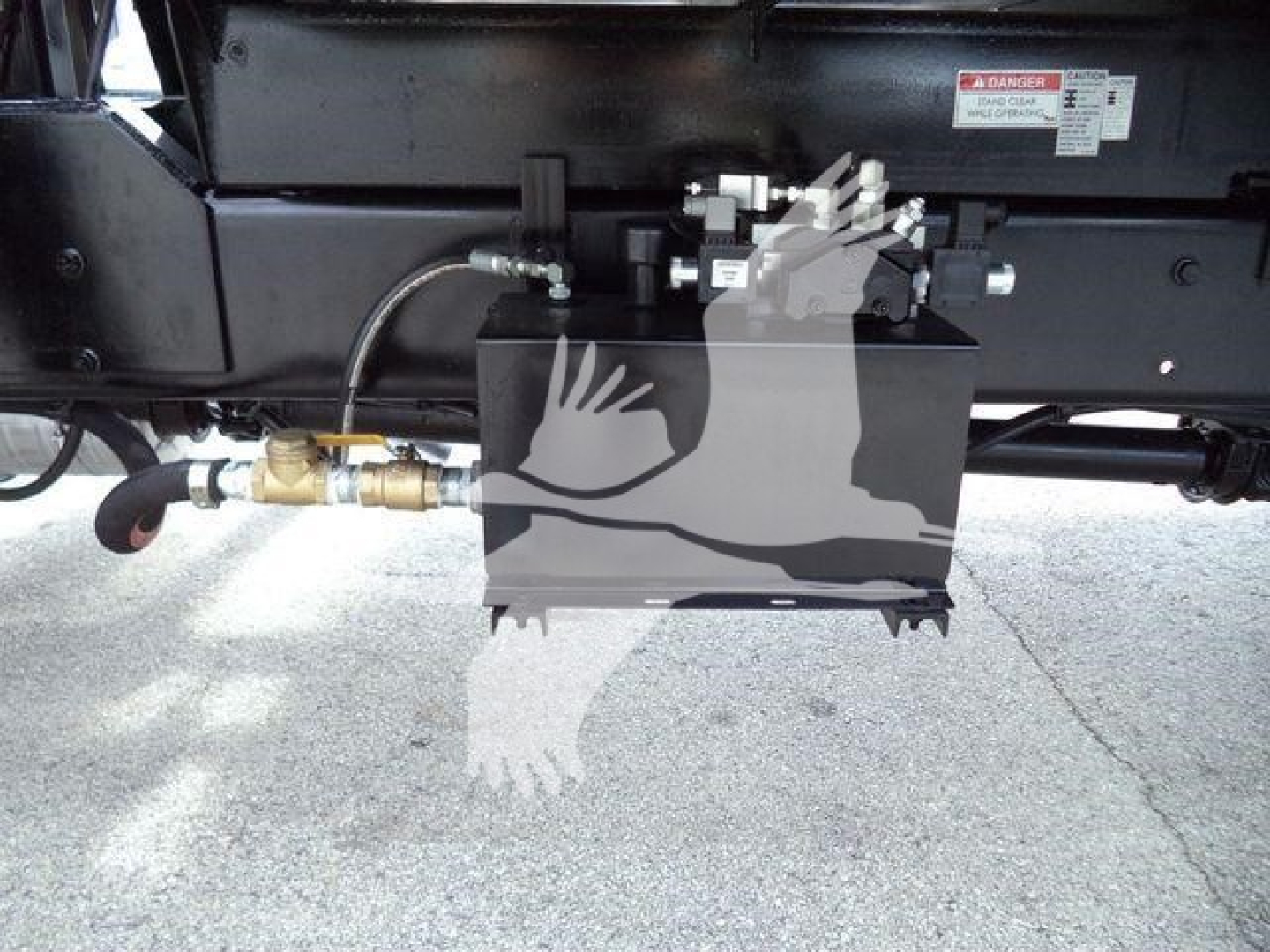 Equipment component mounted under a 2019 International 4300 grapple truck showing hydraulic lines and control box with labels.