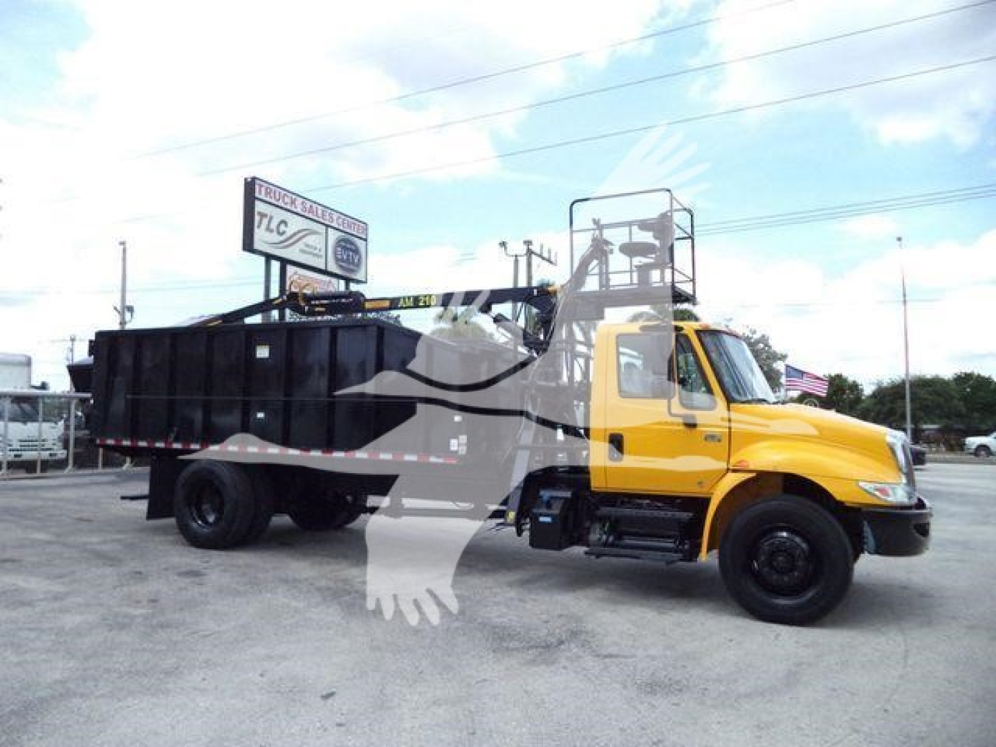2019 International 4300 grapple truck in yard, yellow cab with black dump bed, stock number visible in listing.