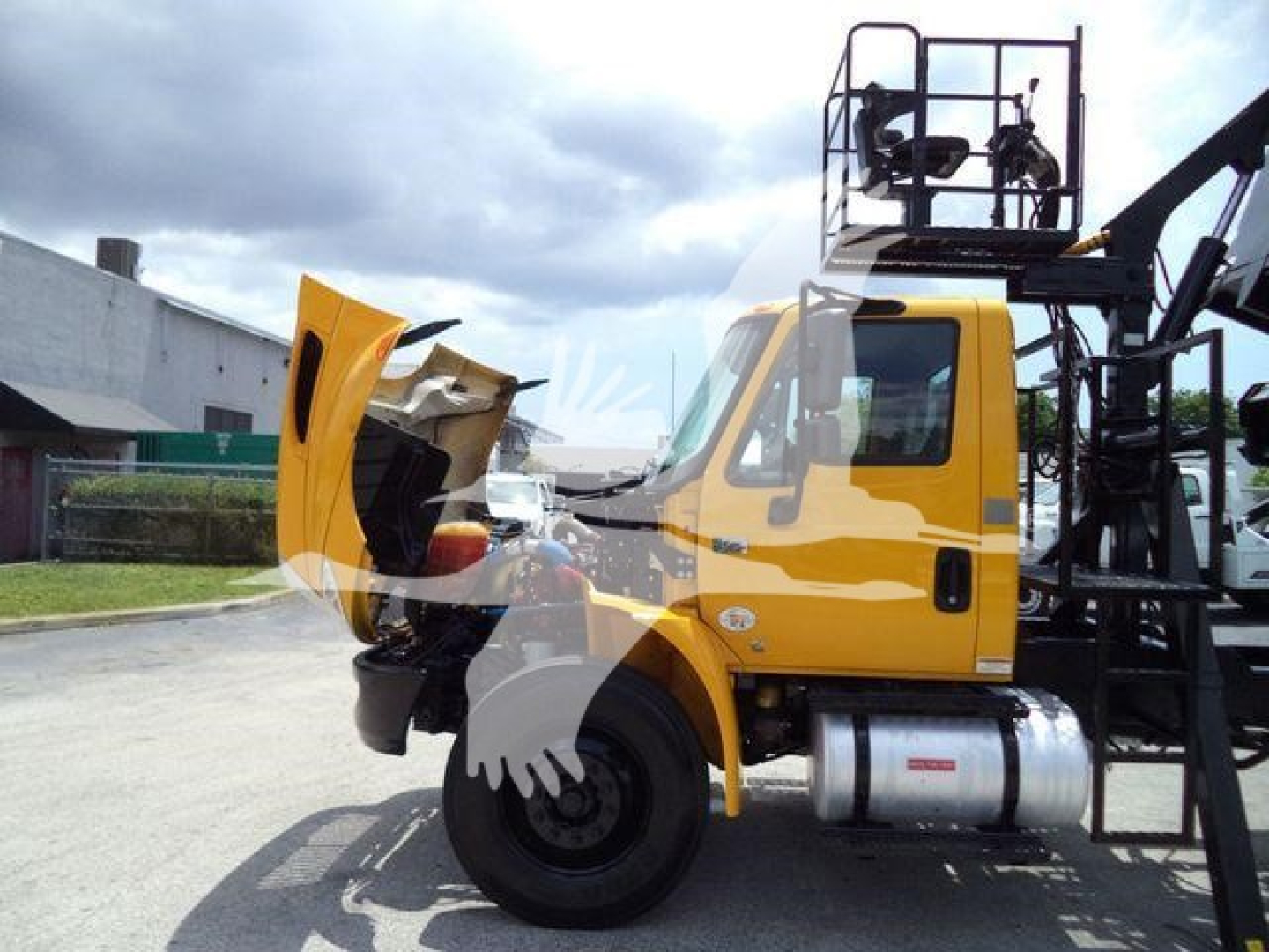Truck cab and grapple crane attachment on a yellow 2019 International 4300 with front hood open.