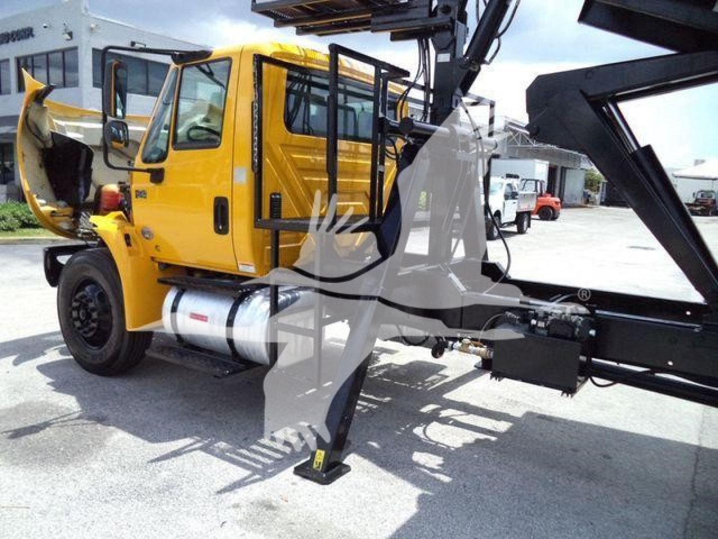 2019 International 4300 grapple truck side view showing yellow cab, open door, hydraulic crane arm and stabilizer legs