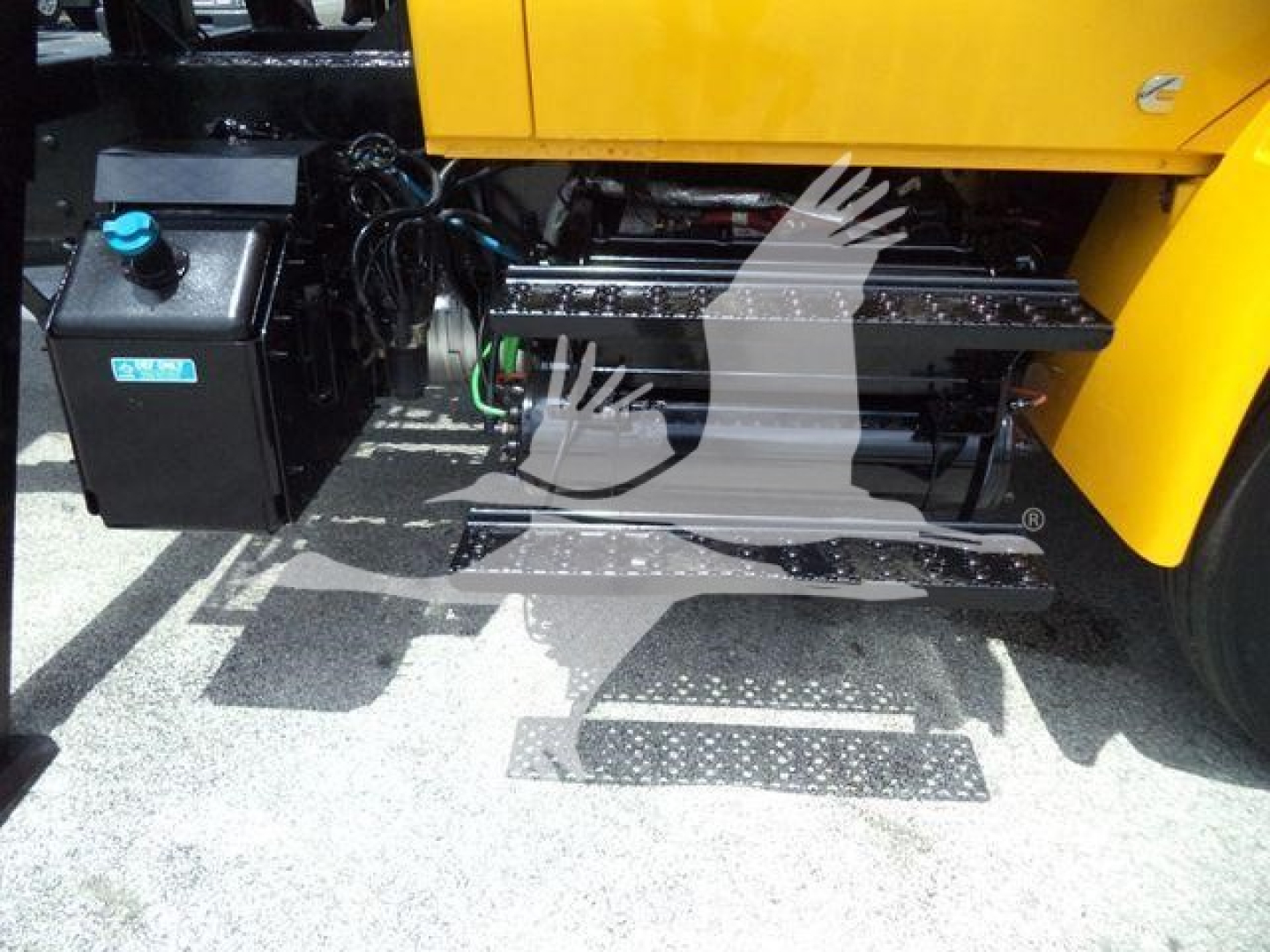 Truck side view showing hydraulic system and steps next to a black battery box and yellow International 4300 cab