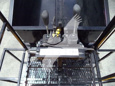 Operator cab view of a hydraulic lever control and forked joystick in a used 2019 International 4300 grapple truck, showing control levers and wiring harness.