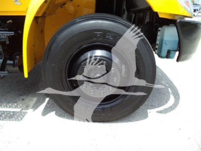 Truck wheel and front fender of a 2019 International 4300 grapple truck showing front tire and yellow body panel.