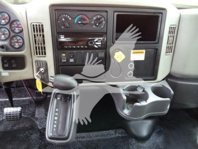 Truck interior dashboard with gauge cluster, center stack, and gear selector showing PRNDL. Bare metal surfaces, cup holder, and a warning label present.
