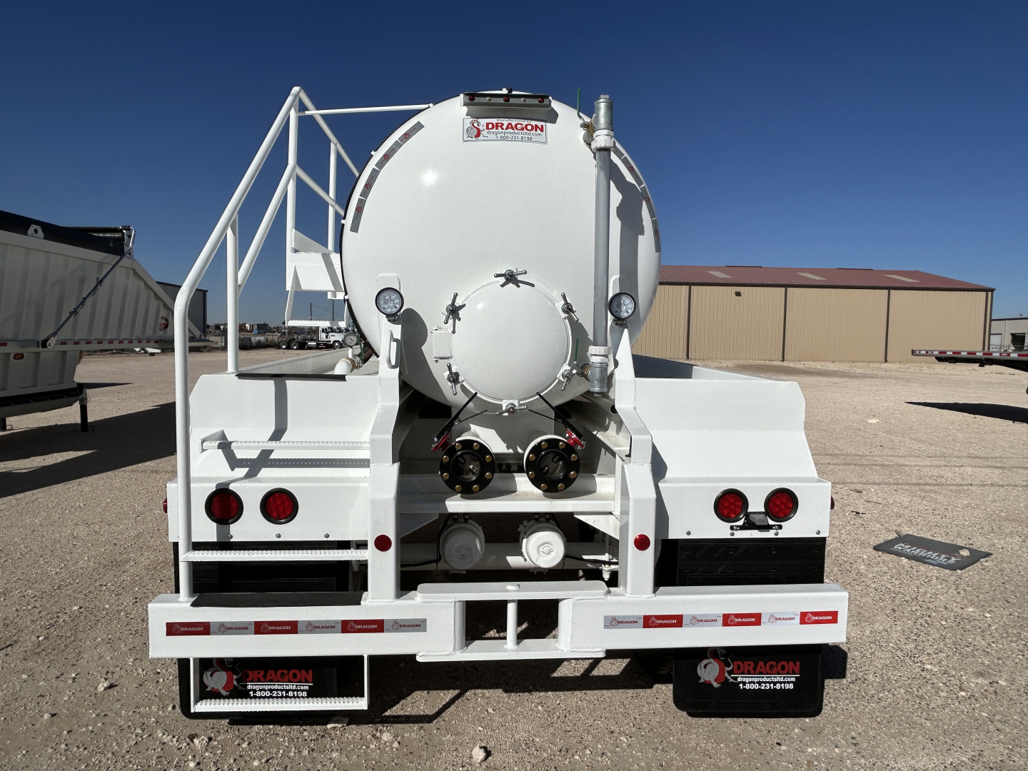 Back view of a Dragon 130BBL vacuum trailer showing rear panels, dual circular lids, and discharge connections.