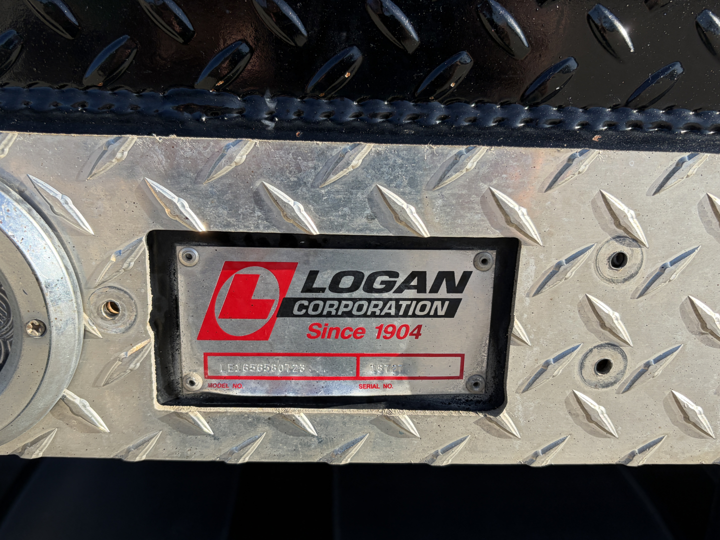 Truck equipment plate on diamond plate with Logan Corporation Since 1904 logo and serial number area visible.