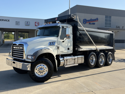 Mack GR64F dump truck with black dump body and white cab, side view showing chrome bumper, dual rear axles, and hoist mechanism.