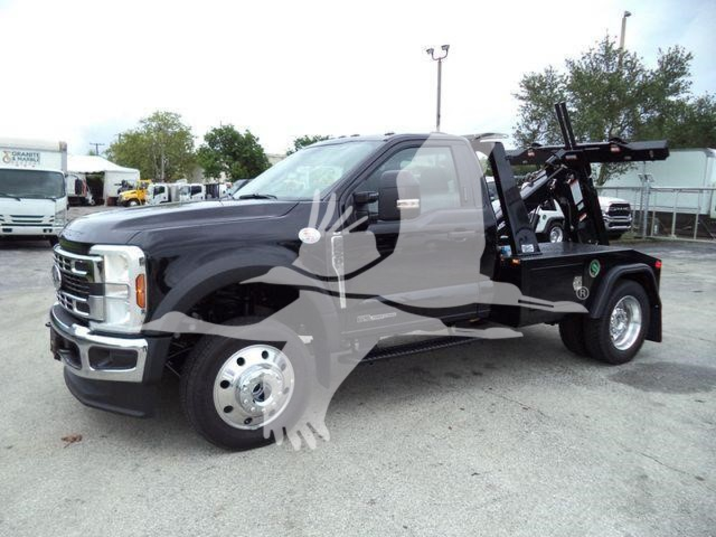 Ford F-450 tow truck with a front cab and flatbed with a winch apparatus in a dealership lot.
