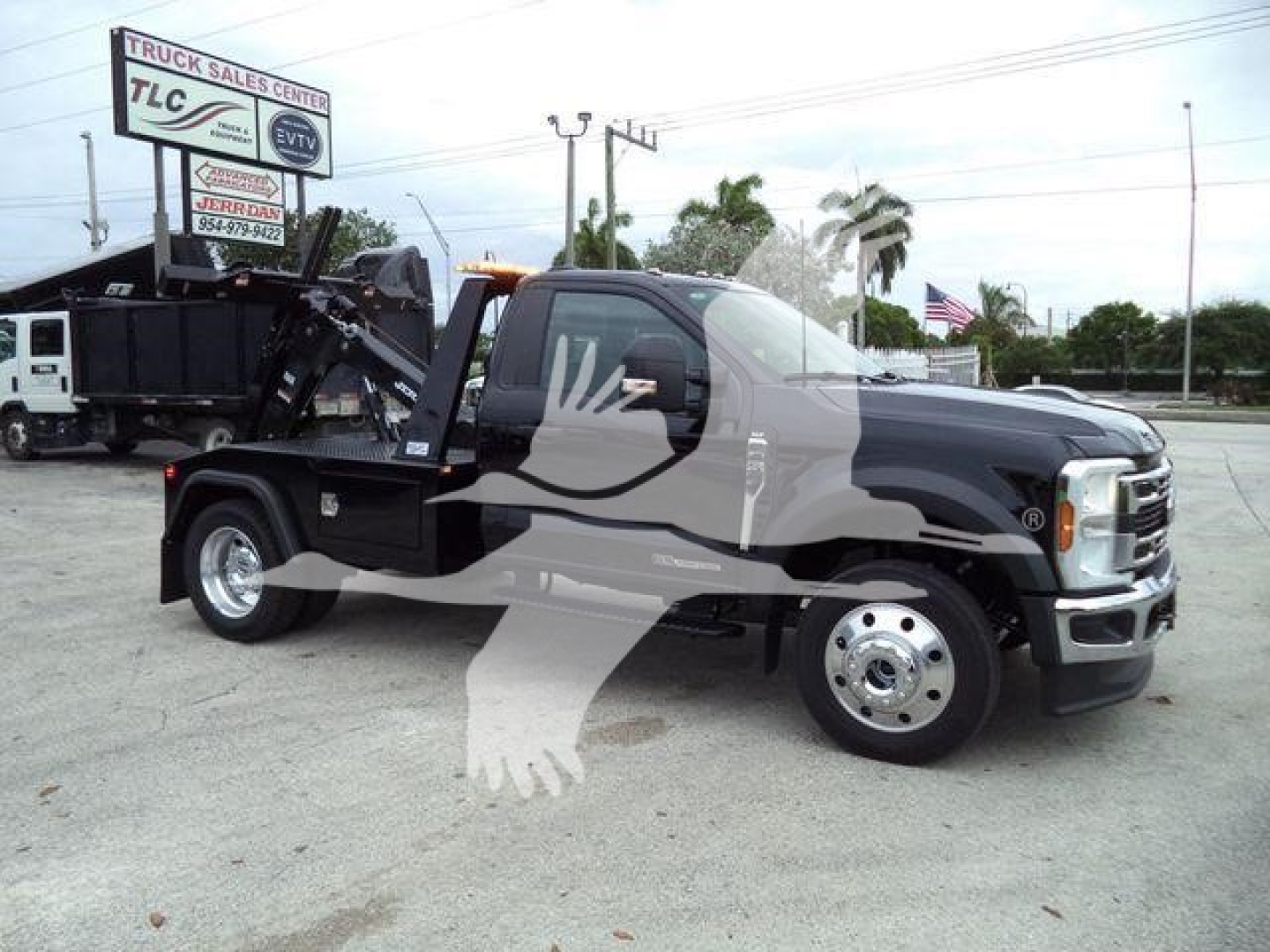 2024 Ford F450 tow truck with a stock wheelbase, black body, flatbed with hydraulic winch system, front chrome bumper, side mirrors, and branding visible in lot.