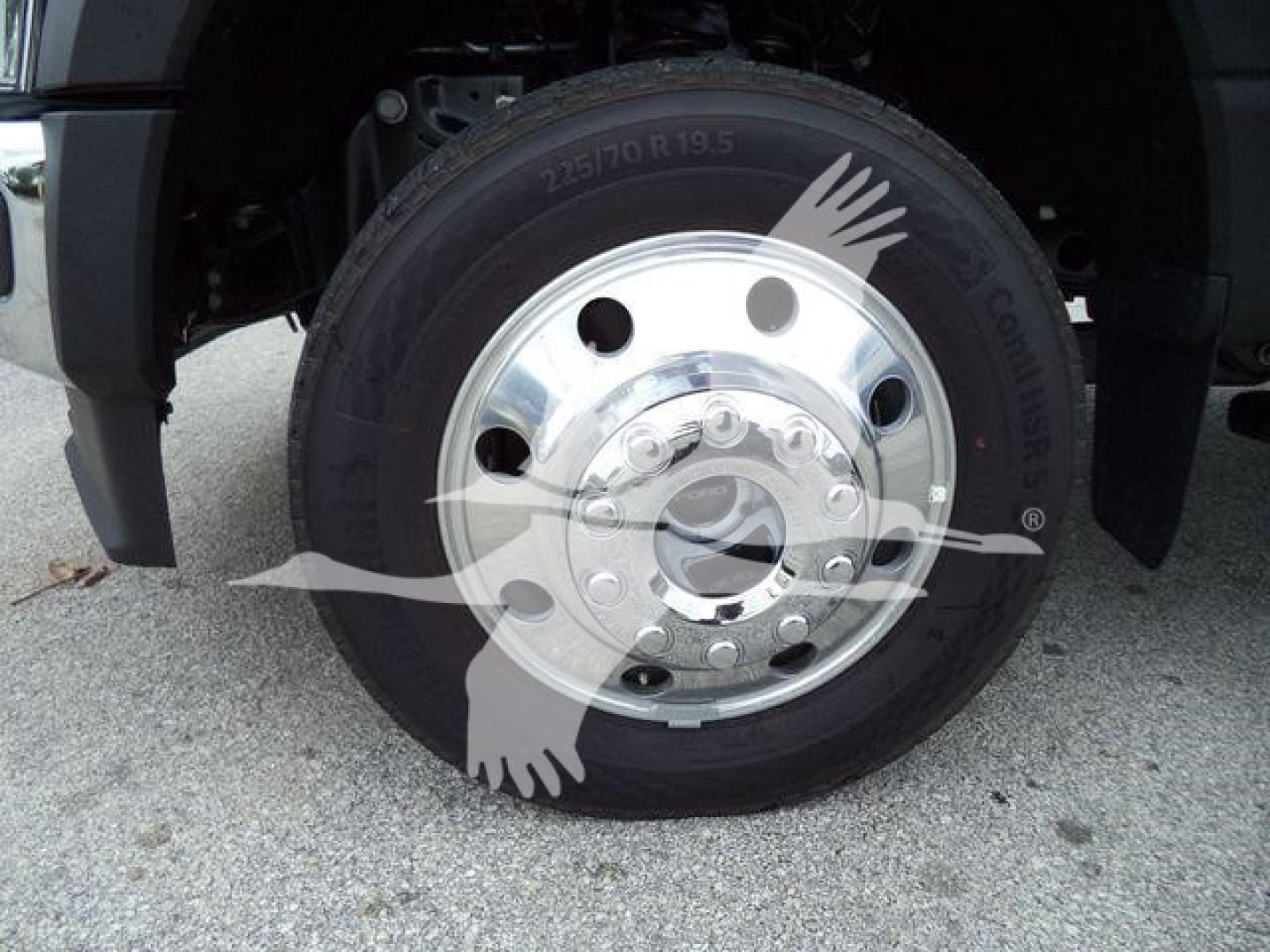 Wheel and tire close-up on a Ford F-450 front hub showing polished steel rim and tire marking 235/80 R19.5