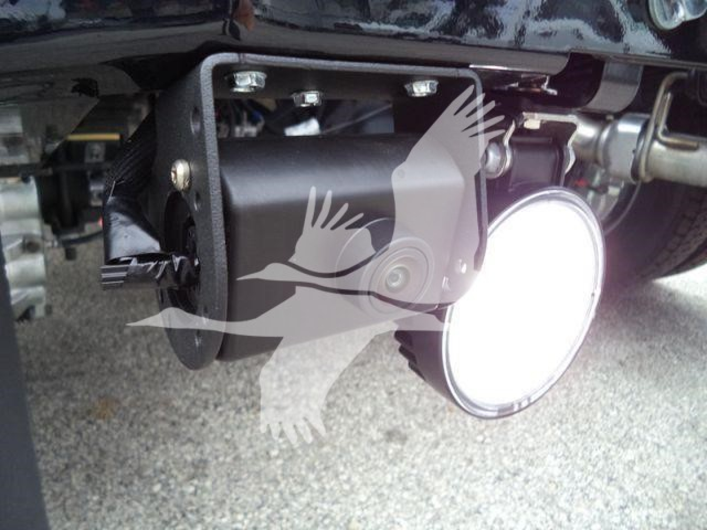 Winch mounting under a Ford F-450 bumper with a round LED work light and mounting hardware visible.