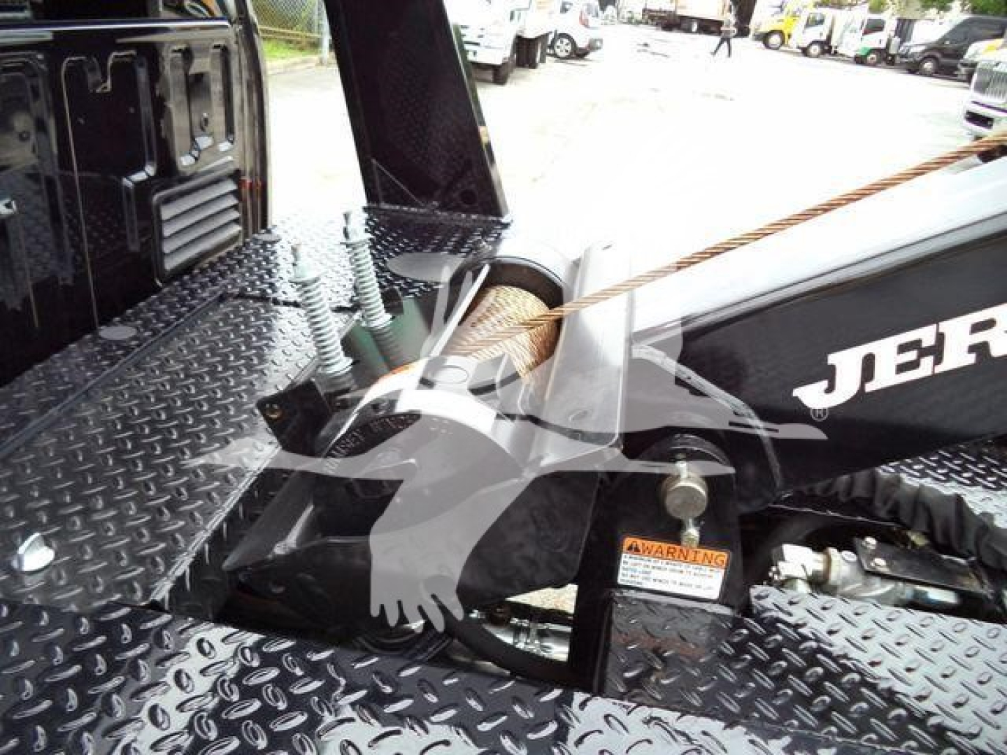 Ford F-450 winch system mounting area with diamond plate surface and warning label visible.