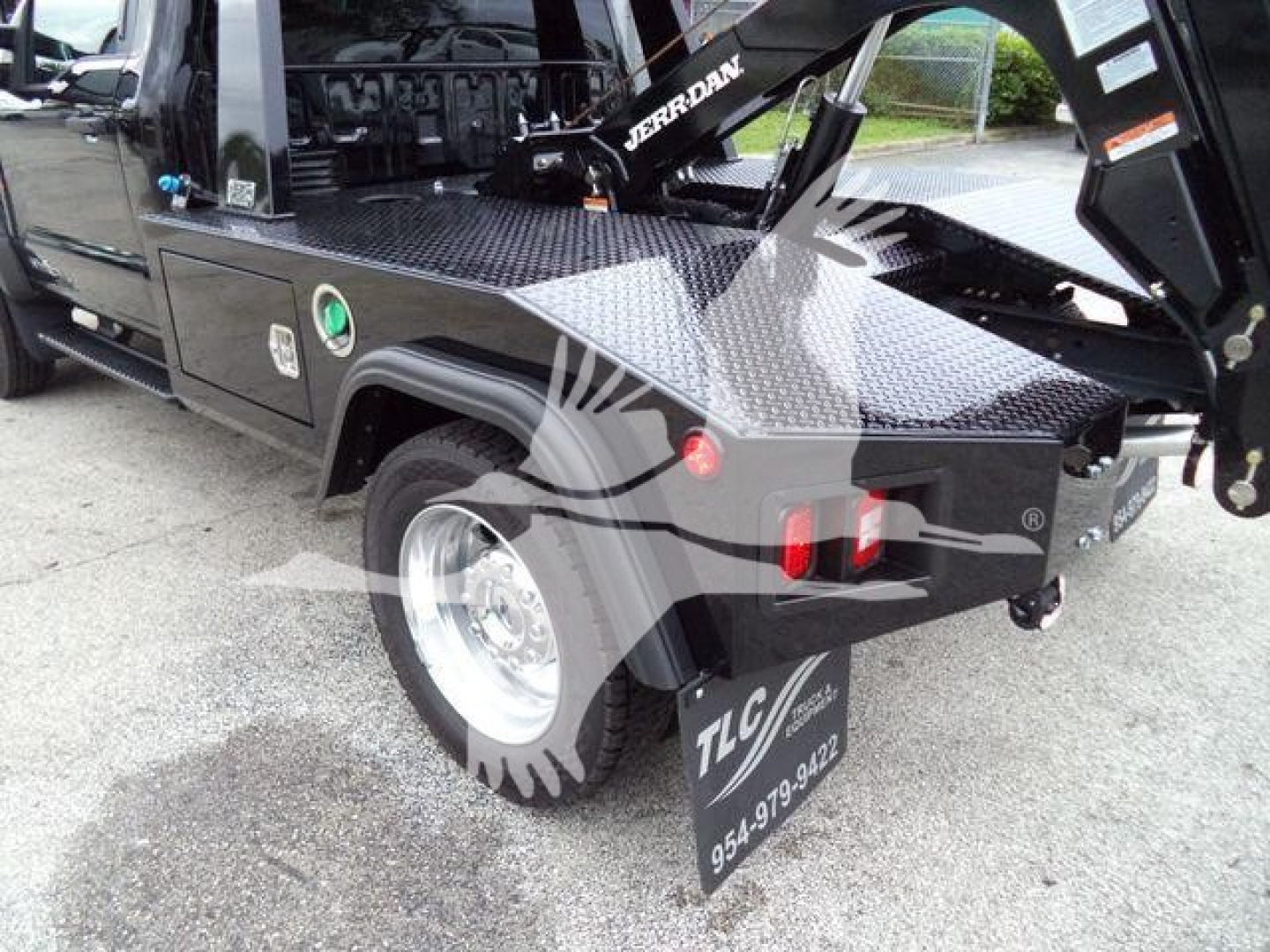 Ford F-450 truck with crane/winch system, diamond plate toolbox, and TCL branding; rear wheel and mudflap visible; tail light cluster and hitch area.