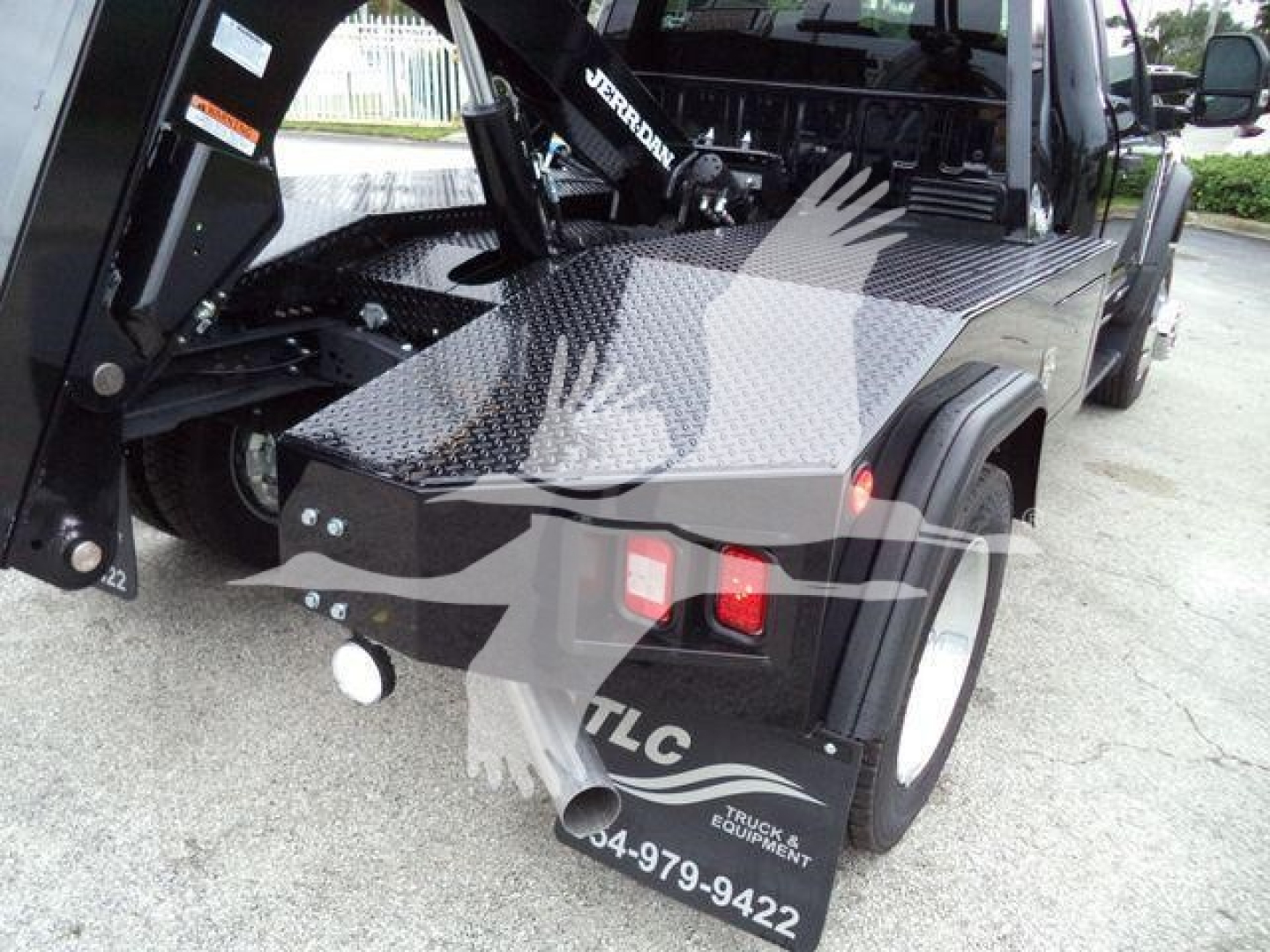 Ford F-450 rear/side view showing diamond plate bed, tow hitch, and winch setup with hydraulic arms visible.