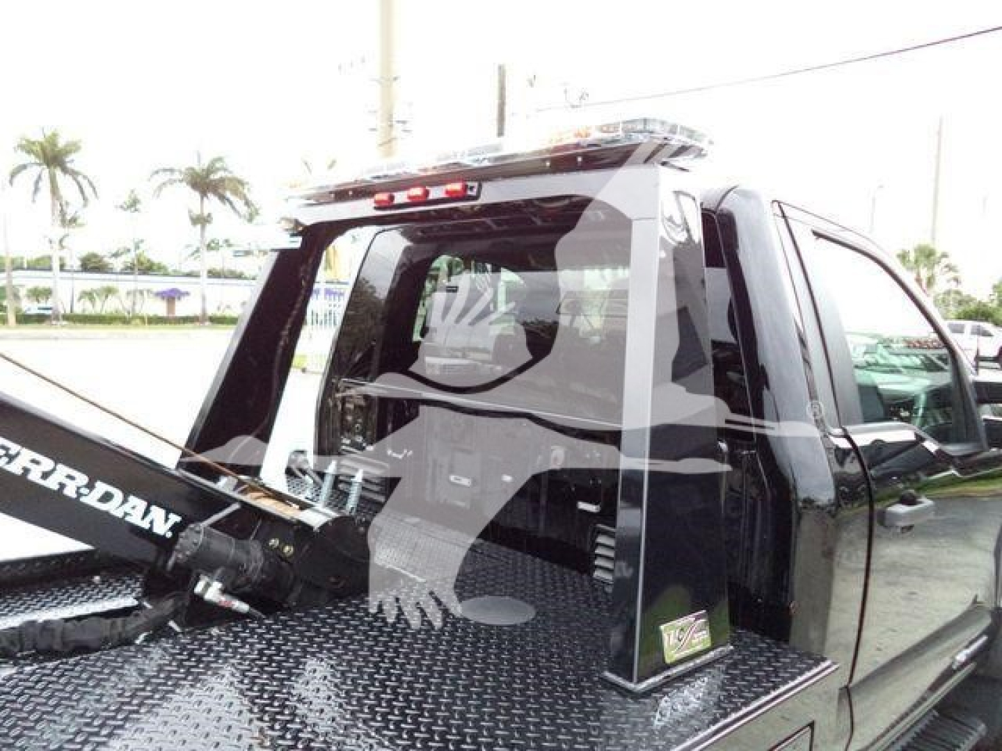Truck bed area of a 2024 Ford F450 with a winch setup and diamond plate bed; rear cab with rear window and light bar visible.