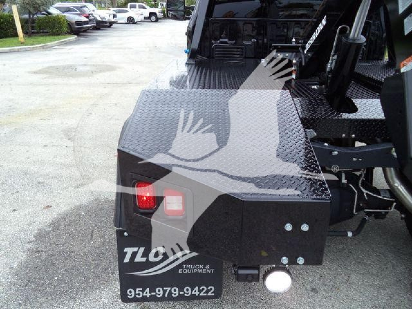 Rear view of a black metal toolbox on a Ford F-450 truck with TLC Truck & Equipment logo, phone number 954-979-9422, and two red/white lights.