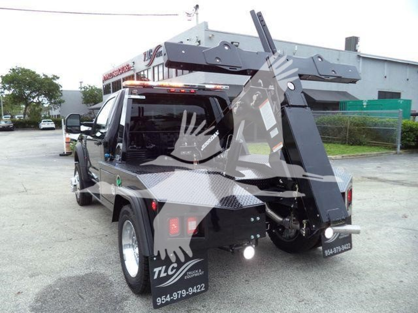 Ford F-450 service truck with hydraulic arm and winch, rear view showing backup lights and TLC branding, stock number J40067FM in a dealership lot.