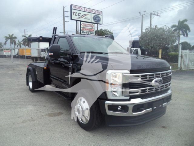Ford F-450 pickup truck in a dealership lot, front three-quarter view with winch category. visible text includes 'TRUCK SALES CENTER' on sign in background and reflections on vehicle.