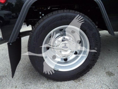 Wheel assembly and tire on a Ford F-450 truck with mud flaps and chrome wheel; partial fender and undercarriage visible.