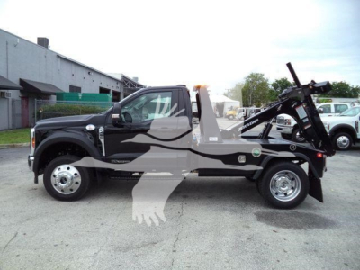 Truck side view showing a 2024 Ford F-450 with a towing/wrecker crane on the rear, single cab, black exterior, steel wheels, stock number J40067FM.