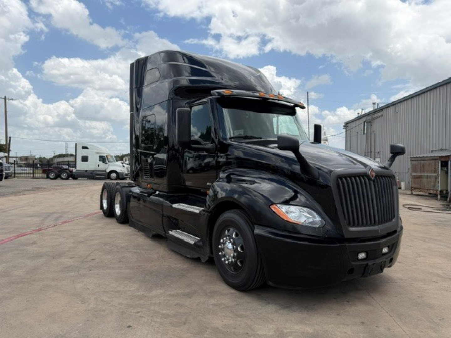 Truck image showing a black 2022 International LT conventional sleeper cab with aerodynamic hood and dual rear axles, front grille, and side mirrors.