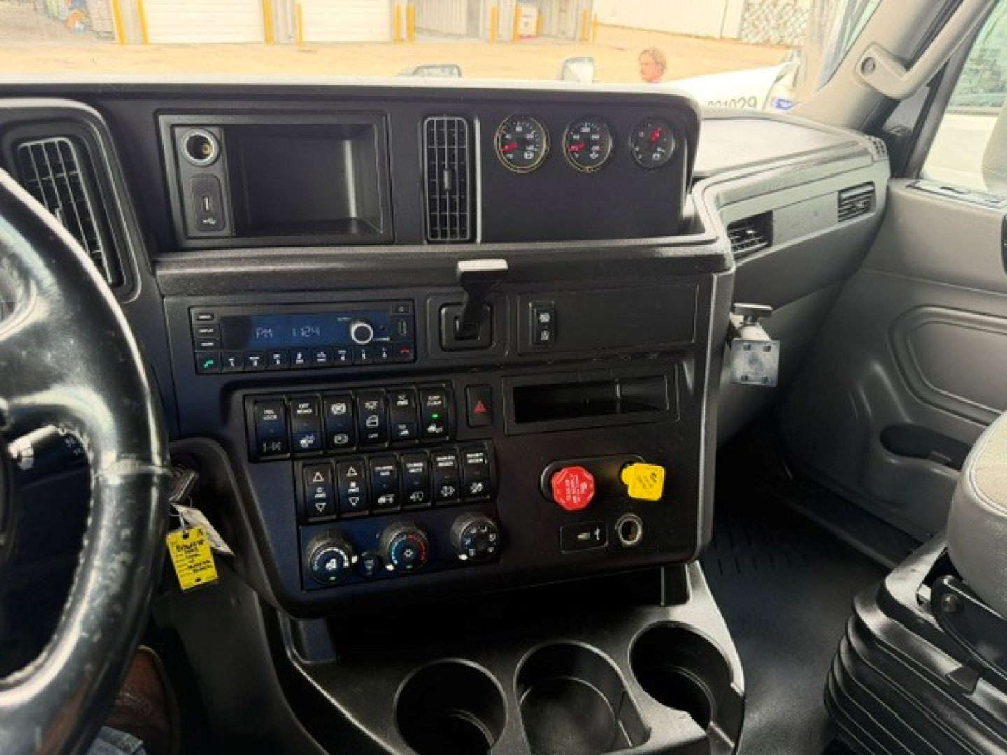 Dashboard in 2022 International LT sleeper cab showing instrument cluster, steering wheel, center console with controls, shifter, and cup holders.