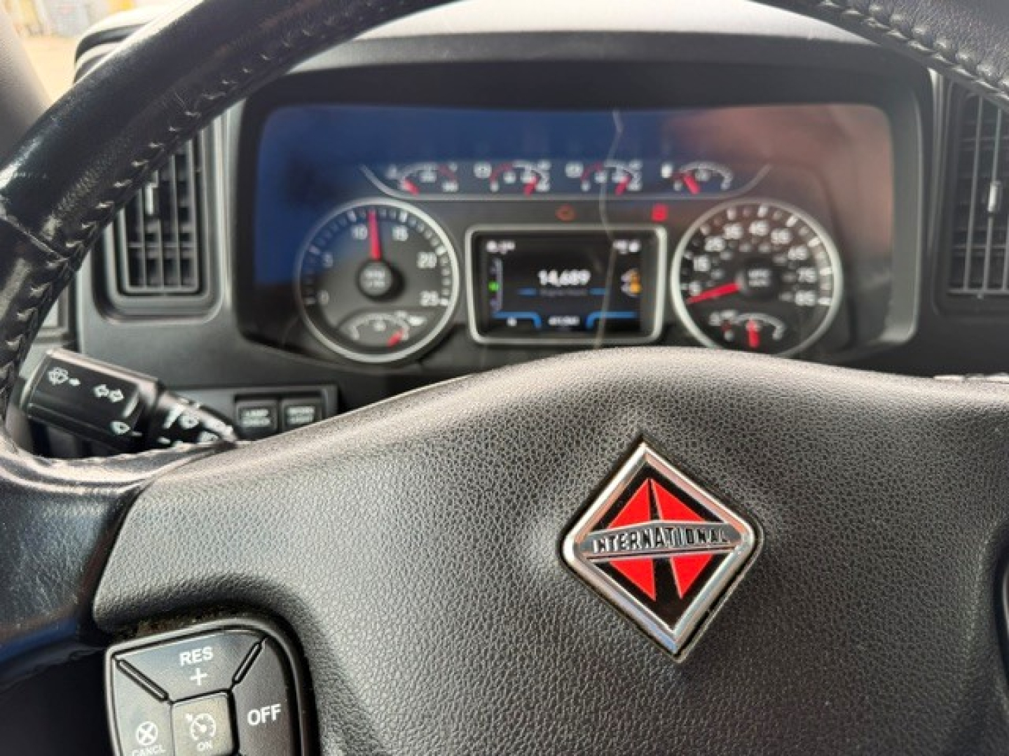Truck interior dash showing instrument cluster and steering wheel with International logo center.