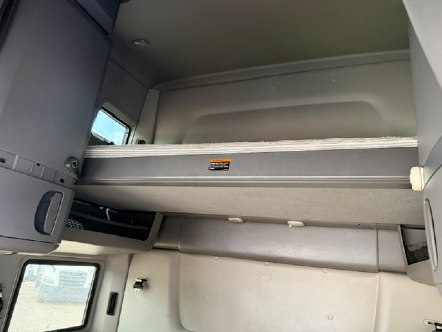 Cab interior of a used 2022 International LT sleeper with a clear view of the upper bunk/bed area and storage shelf.