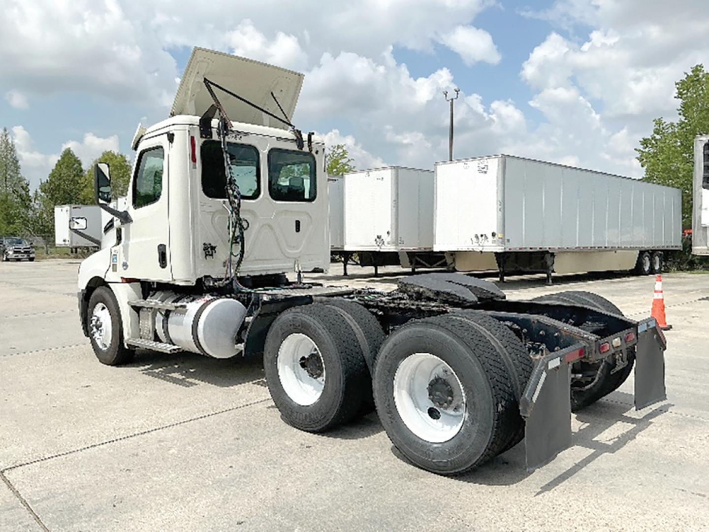 Freightliner Cascadia126 daycab tractor rear wheel view showing fifth wheel and dual rear axles with attached chrome exhaust and sleeper cab.